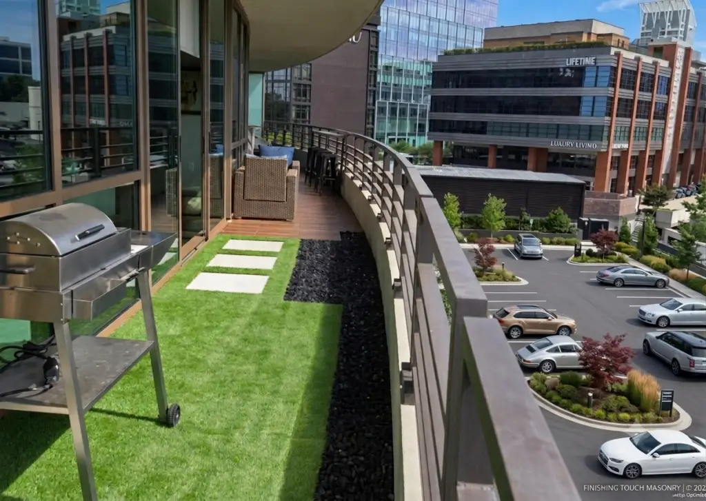 Modern condo balcony featuring lush synthetic turf, light porcelain pavers, dark river rock gravel border, and rich wood flooring.